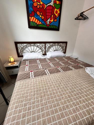 a bed in a room with a painting on the wall at Pousada Suítes Do Pelô in Salvador