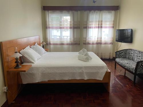 a bedroom with a bed and a chair and a television at Casa do Ilhéu in Vila Franca do Campo