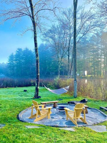 a park with two chairs and a picnic table and a hammock at In the clouds your cozy- lake house in Swan Lake