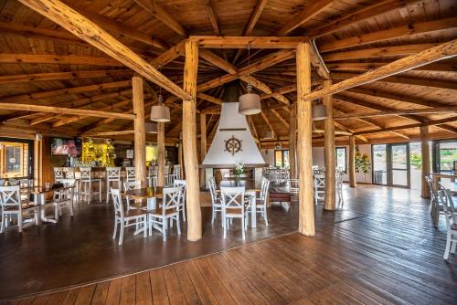 ein Esszimmer mit Holzdecken sowie Tischen und Stühlen in der Unterkunft Łejkówka in Wólka Magierowa