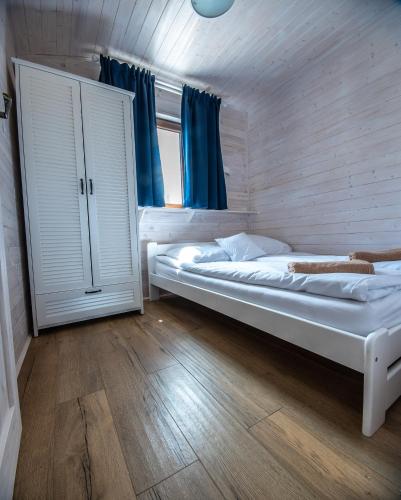 a bedroom with two beds and a window with blue curtains at Łejkówka in Wólka Magierowa