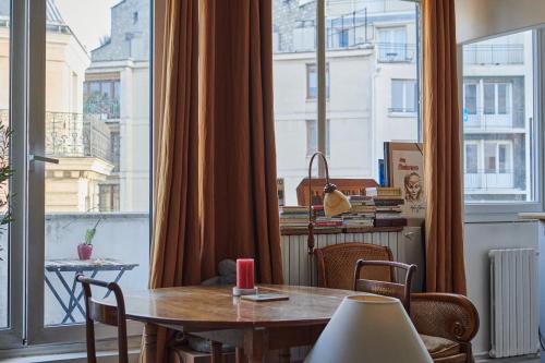 une salle à manger avec une table et une grande fenêtre dans l'établissement Studio cosy avec balcon Paris 16ème, à Paris