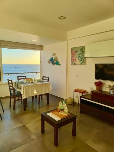 a living room with a table and a view of the ocean at Acqua Marine in Sesimbra