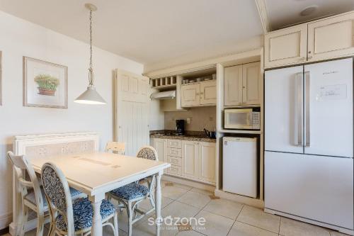 a kitchen with a table and a white refrigerator at Studios frente ao mar no IL Campanario Resort ILCTOP in Florianópolis