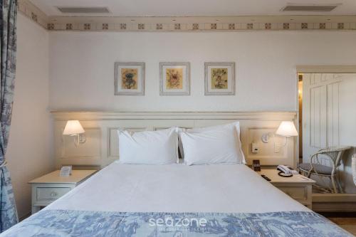 a bedroom with a white bed with two pillows at Studios frente ao mar no IL Campanario Resort ILCTOP in Florianópolis