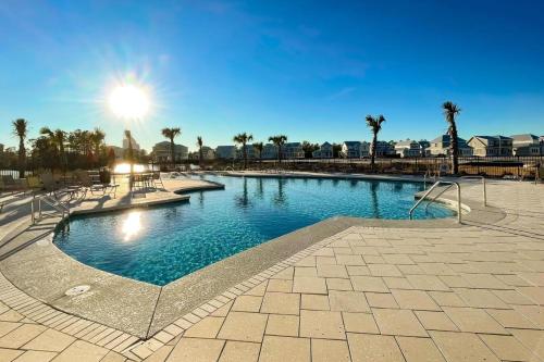 a large swimming pool with palm trees and the sun at High Tides in Orange Beach
