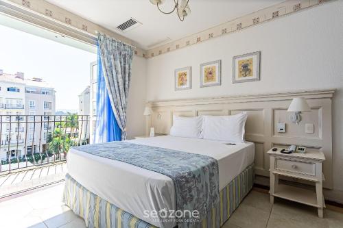 a bedroom with a bed and a large window at Studios frente ao mar no IL Campanario Resort ILCTOP in Florianópolis