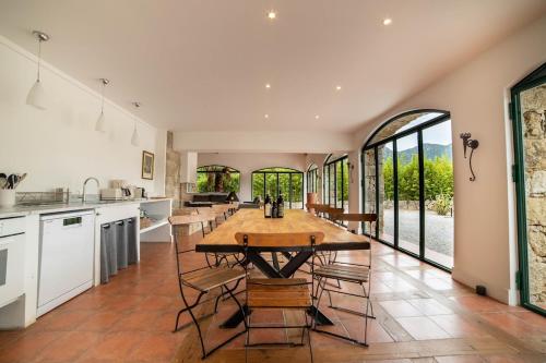 una cucina con un grande tavolo e sedie in legno di La tonnelerie, belle villa pour 9 personnes au coeur d'un vignoble avec piscine a Sartène