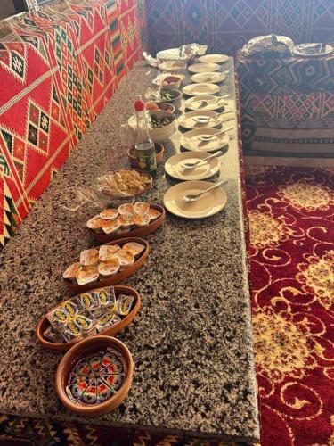 a long table filled with plates and bowls of food at مخيم وهج رم in Disah