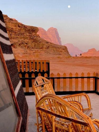 two wicker chairs sitting on a balcony overlooking the desert at مخيم وهج رم in Disah
