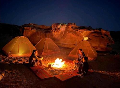 a group of people sitting around a fire in front of tents at مخيم وهج رم in Disah