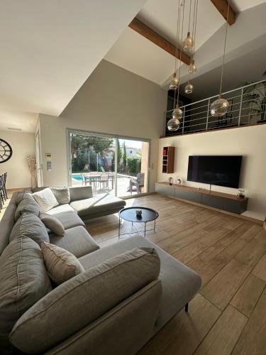 un grand salon avec un canapé et une télévision dans l'établissement Maison paisible toute équipée, piscine chauffée, à Sallèles-dʼAude