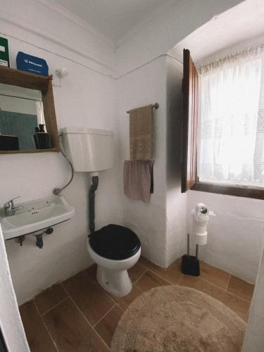 a bathroom with a toilet and a sink and a window at A Casa DAvo in Estremoz