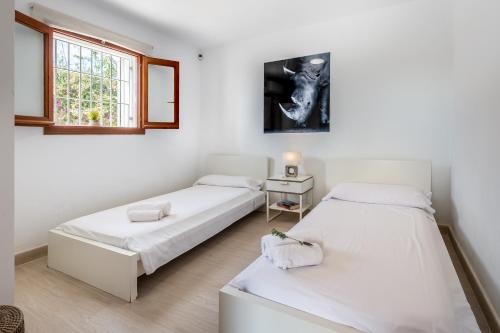 two beds in a room with white walls and a window at New! Villa Air - Cerca de Ibiza - BBQ in Illes Balears