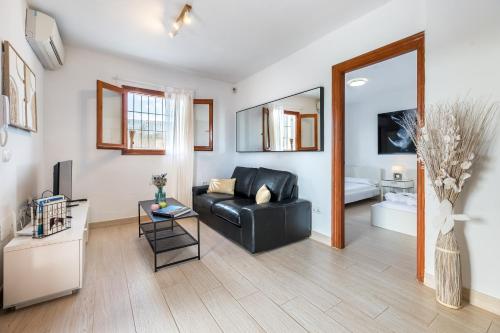 a living room with a black leather couch and a mirror at New! Villa Air - Cerca de Ibiza - BBQ in Illes Balears
