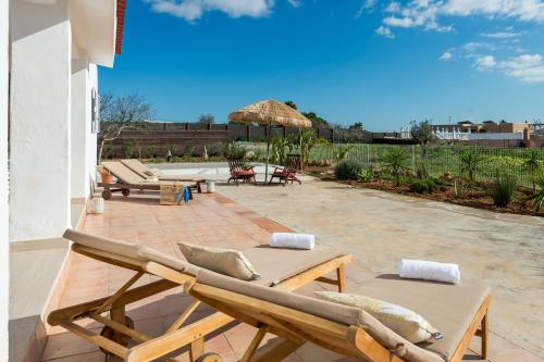 a patio with two lounge chairs and an umbrella at New! Villa Air - Cerca de Ibiza - BBQ in Illes Balears