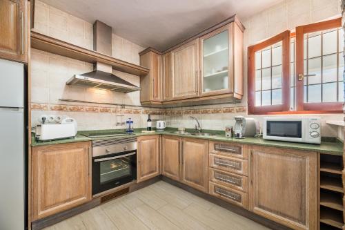 a kitchen with wooden cabinets and a stove top oven at New! Villa Air - Cerca de Ibiza - BBQ in Illes Balears
