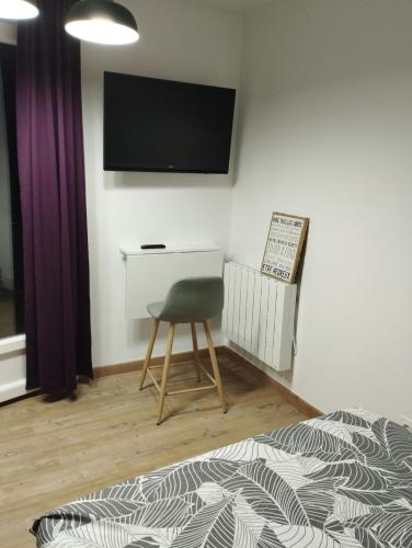 Cette chambre dispose d'une chaise et d'une télévision murale. dans l'établissement La room, à Joué-lès-Tours