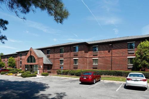 a brick building with a red car parked in a parking lot at Suburban Studios-Cary in Cary