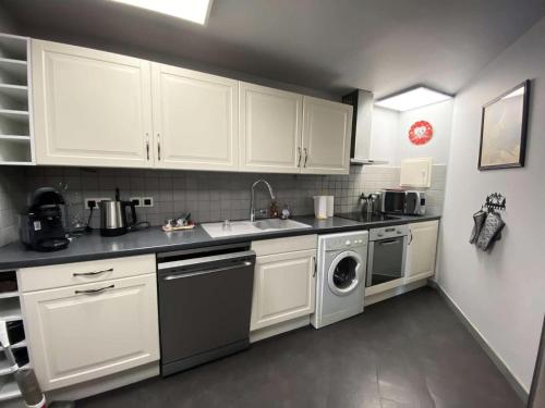 une cuisine avec des armoires blanches et une laveuse et une sécheuse dans l'établissement Résidence Diamant 1 - Spacieux appartement en plein centre de la station des Deux Alpes MAE-1201, à Vénosc