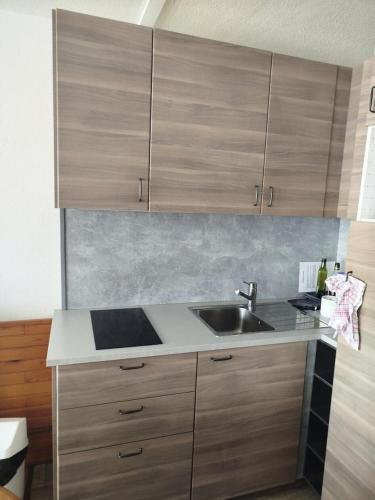 une cuisine avec un évier et des armoires en bois dans l'établissement Résidence Le Tourmalet - maeva Home - Appartement 3 pièces 8 personnes - Confort MAE-0651, à La Mongie