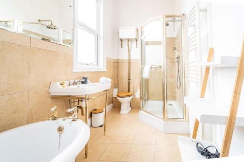 a bathroom with a tub and a sink and a toilet at Swift Host - 4 Bedrooms - Beautiful Period Property - Parking - Garden in Norwich