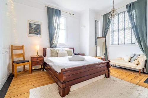 a bedroom with a bed and a chair and windows at Swift Host - 4 Bedrooms - Beautiful Period Property - Parking - Garden in Norwich