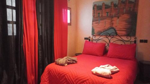 a bedroom with a red bed with two towels on it at Ferme Tibrijine in Marrakech