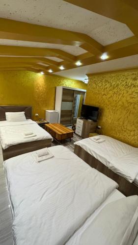 a room with three beds in a room with a yellow wall at Hotel Premium in Pristina