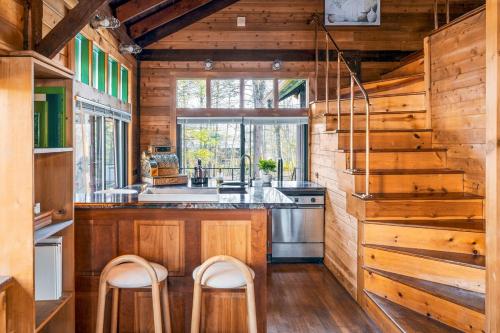 米尔福德Couple's Retreat Lodge with Hot Tub and River Views的厨房设有木墙和带凳子的台面。