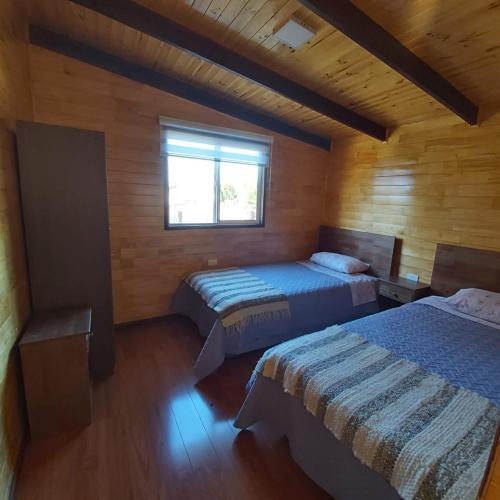 a bedroom with two beds and a window at Cabaña Encanto del humedal Aituy in Aytuy