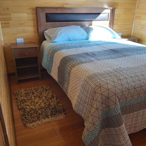 a bedroom with a bed and a nightstand next to a bed sidx sidx sidx at Cabaña Encanto del humedal Aituy in Aytuy