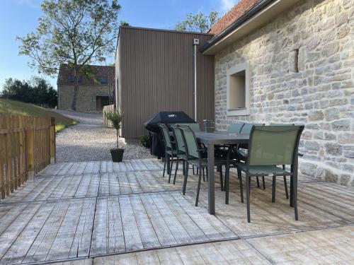 un patio avec une table et des chaises et un mur de briques dans l'établissement Les pins qui chuchotent, à Offrethun