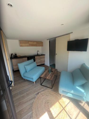 un salon avec des meubles bleus et une télévision à écran plat dans l'établissement Studio indépendant et équipé proche Circuit des 24h et Pôle Européen du Cheval, à Parence