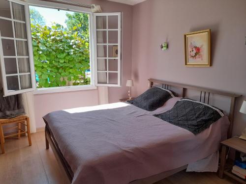 une chambre avec un lit et une grande fenêtre dans l'établissement maison quercynoise FIGEAC, à Lunan
