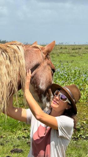 a woman is petting a horse in a field at Los Chajá Ecolodge in Barra de Valizas