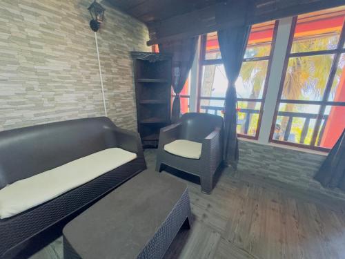 a room with a couch and a chair and windows at Hanna Suites in Panajachel