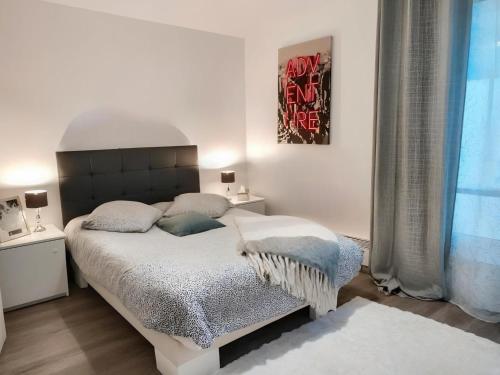 une chambre blanche avec un grand lit et une fenêtre dans l'établissement Kinkala, charmant 2 pièces à 20 minutes de Paris, au Blanc-Mesnil