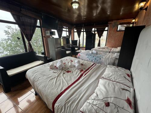 a room with three beds and a couch and windows at Hanna Suites in Panajachel