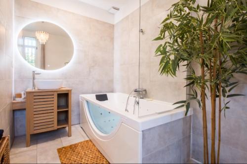 La salle de bains est pourvue d'une baignoire et d'une plante en pot. dans l'établissement Appartement détente avec jacuzzi et piscine, à Perpignan
