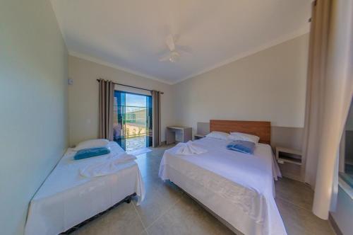 two beds in a room with a window at Espaço premium, Casa com 5 quartos, piscina aquecida & Jacuzzi in Caldas Novas