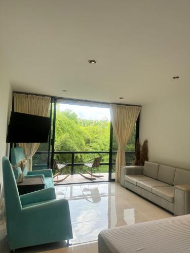 a living room with a couch and chairs and a balcony at Hotel Terra Tacuara in Armenia