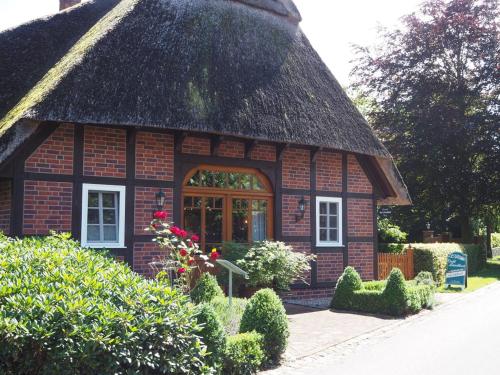 a small brick house with a thatched roof at Ferienhof Hage in Hüde