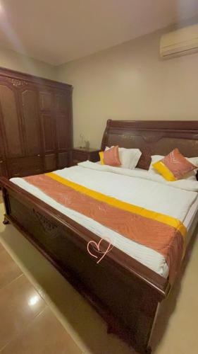 a large bed in a bedroom with a wooden headboard at فيلا العزيزيه - الخبر in Al ‘Azīzīyah