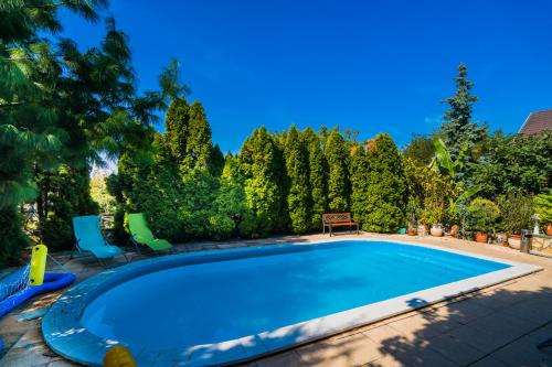 a swimming pool in a yard with chairs and trees at Katica Vendégház in Siófok