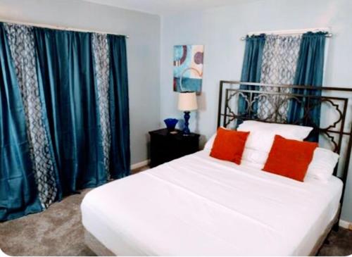 a bedroom with a bed with blue curtains and red pillows at Charles Stays in Kansas City