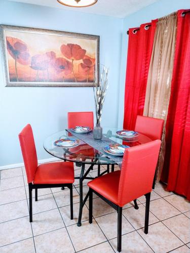 a dining room with a glass table and red chairs at Charles Stays in Kansas City