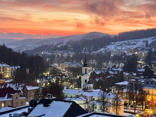 uitzicht op een stad met met met sneeuw bedekte daken en een kerk bij Widok Marzeń Sun&Ski Romantic Art House z garażem in Krynica Zdrój