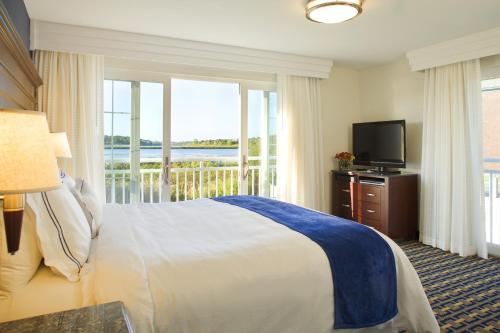 um quarto com uma cama, uma televisão e uma varanda em Newport Beach Hotel & Suites em Middletown