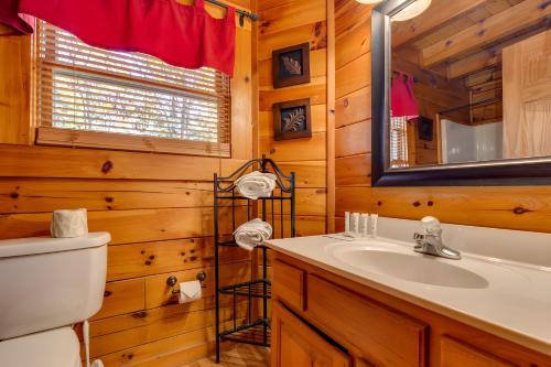 a bathroom with a sink and a toilet and a mirror at Thistle Britches, Secluded Mountain Cabin with Stunning Mountain Views, 1 Acre Next to Dollywood, Hot Tub, Pet Friendly in Sevierville